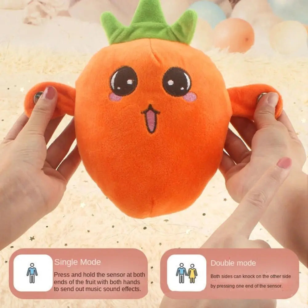 An orange fruit plush toy is being held by hands, demonstrating a single mode where pressing the sensor makes music sound eff