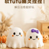 Two white ghost-shaped stress balls with smiling faces resting on a wooden surface.
