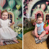 A baby girl dressed in a white dress posing in an underwater castle mermaid theme party backdrop with pink balloons and green