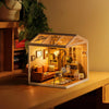 A miniature house kit featuring a cozy living lounge interior with LED lighting displayed on a wooden surface.