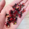 A handful of deep red and amber colored sakura flower crystal glass beads for jewelry making