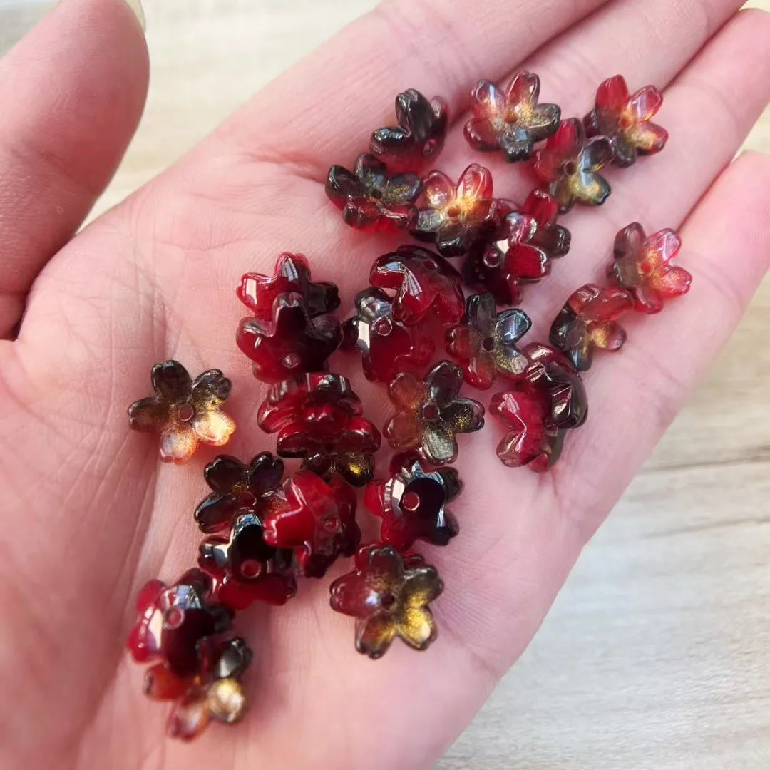 A handful of deep red and amber colored sakura flower crystal glass beads for jewelry making