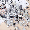A collection of mixed resin rhinestone pearls with an AB finish in various sizes and shades of silver, black, and clear.