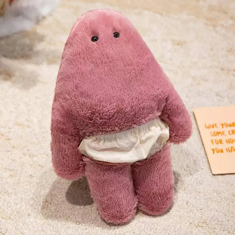 A soft, pink monster plush doll with a belly cutout and pants is shown on a light background.