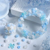 A white and blue camellia bowknot resin shaker filler wreath surrounded by small floral elements and craft supplies.