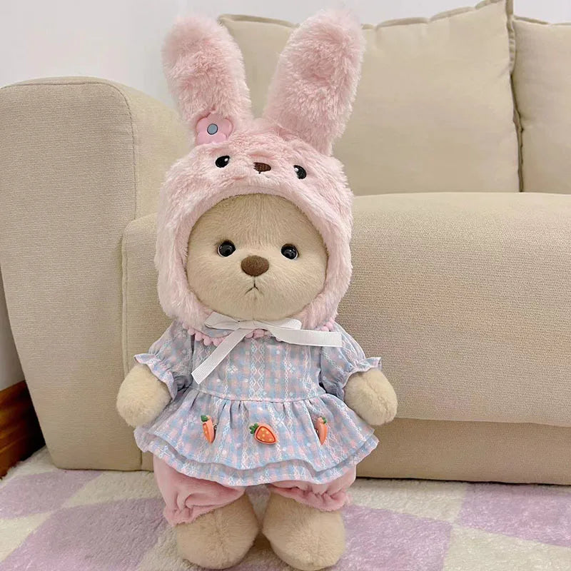 A pink bunny plush doll wearing a light blue and white checkered dress with orange fruit accents.