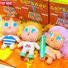 A collection of Crybaby Vacation Mode On vinyl figures in various colors and outfits displayed on an orange background.