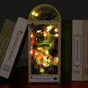 A box of the Firefly Forest DIY miniature wooden dollhouse kit with furniture displayed next to other similar boxes.
