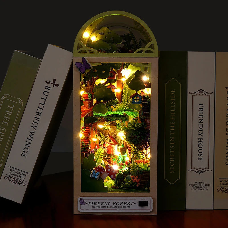 A box of the Firefly Forest DIY miniature wooden dollhouse kit with furniture displayed next to other similar boxes.