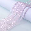 A close-up of light pink faceted crystal beads strung together, displayed on a white surface.