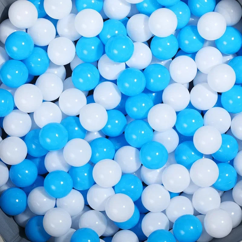 A close-up view of a bulk set of colorful plastic ocean ball pit toys in blue and white.
