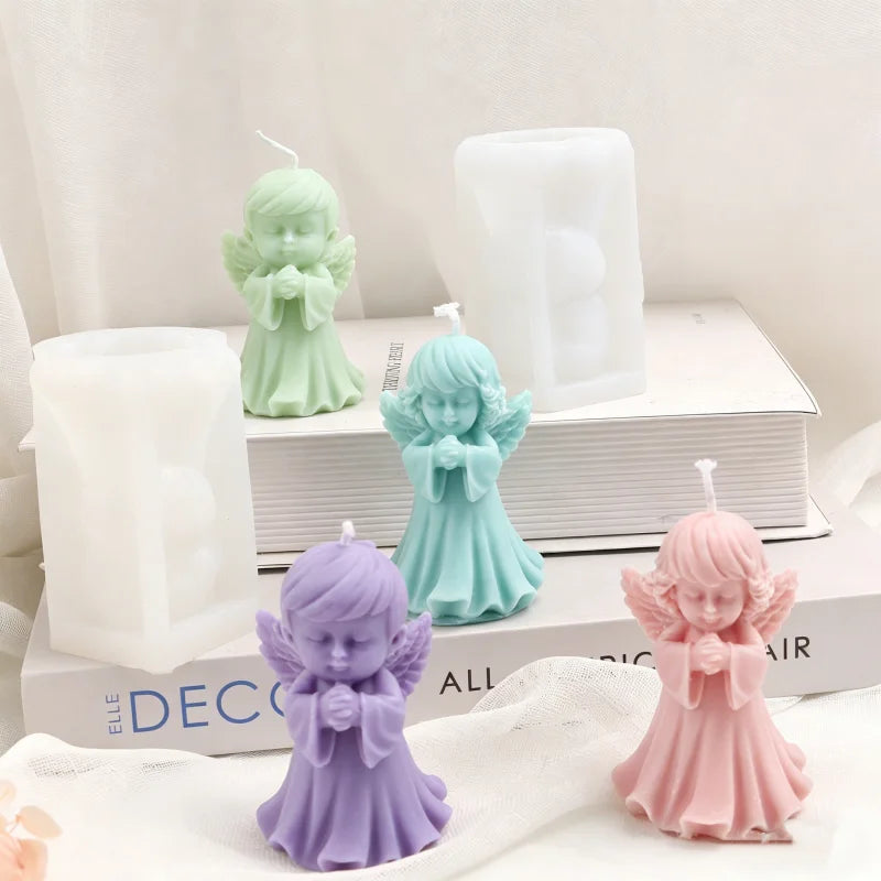 A collection of purple, mint green, and pink silicone praying angel molds for candles and resin displayed on a white box.