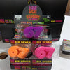 A collection of Nee Doh Squeeze Six Seven toys in various colors including orange and pink, packaged in black boxes.