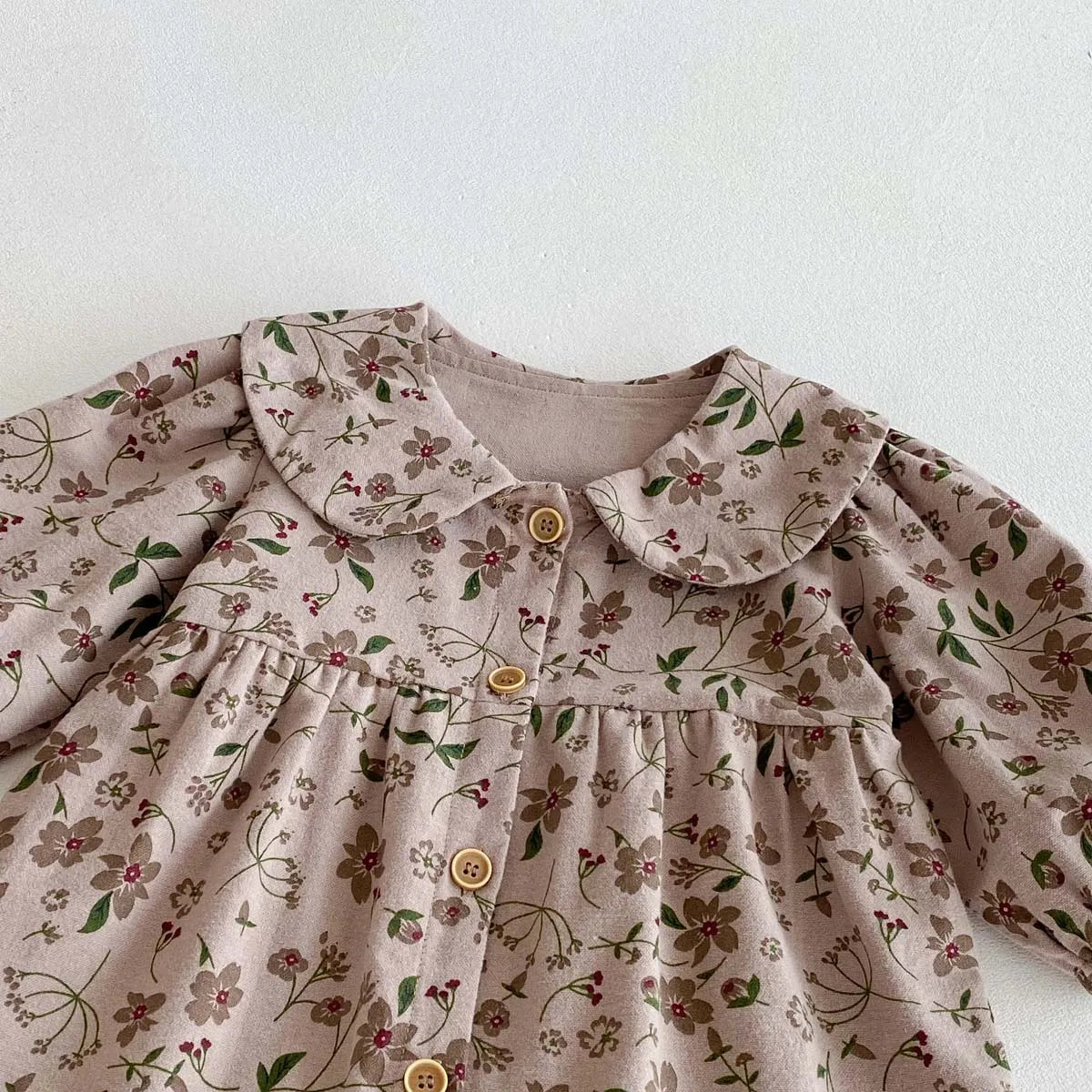 A light pink floral print baby girl jumpsuit with a doll collar and long sleeves.
