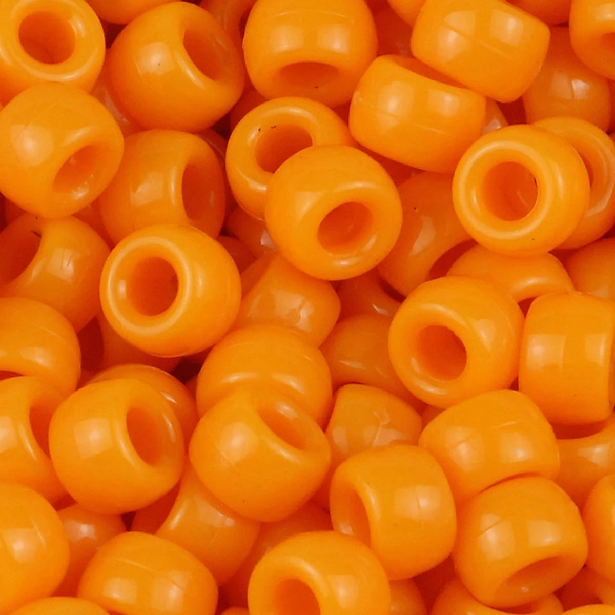 A close-up view of small, round, orange pony beads for jewelry making and crafts.