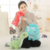 A woman holds a pink dinosaur plush toy and a light green dinosaur plush toy in a bright indoor setting.