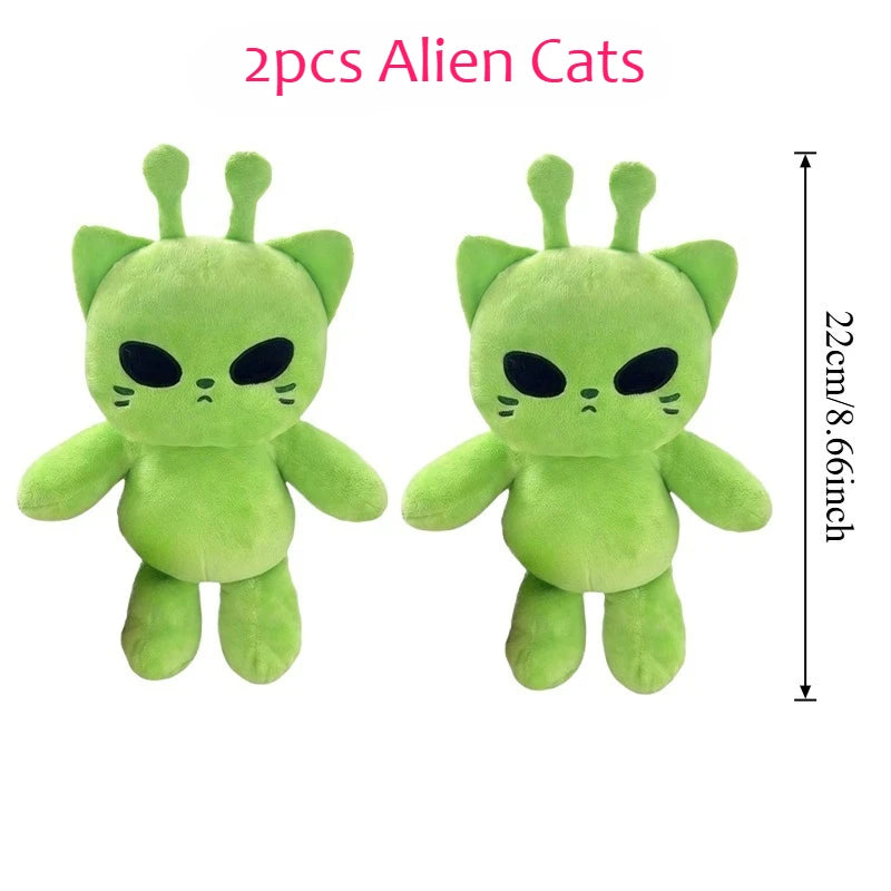 A pair of green alien cat plush toys with black eyes and pointed ears.