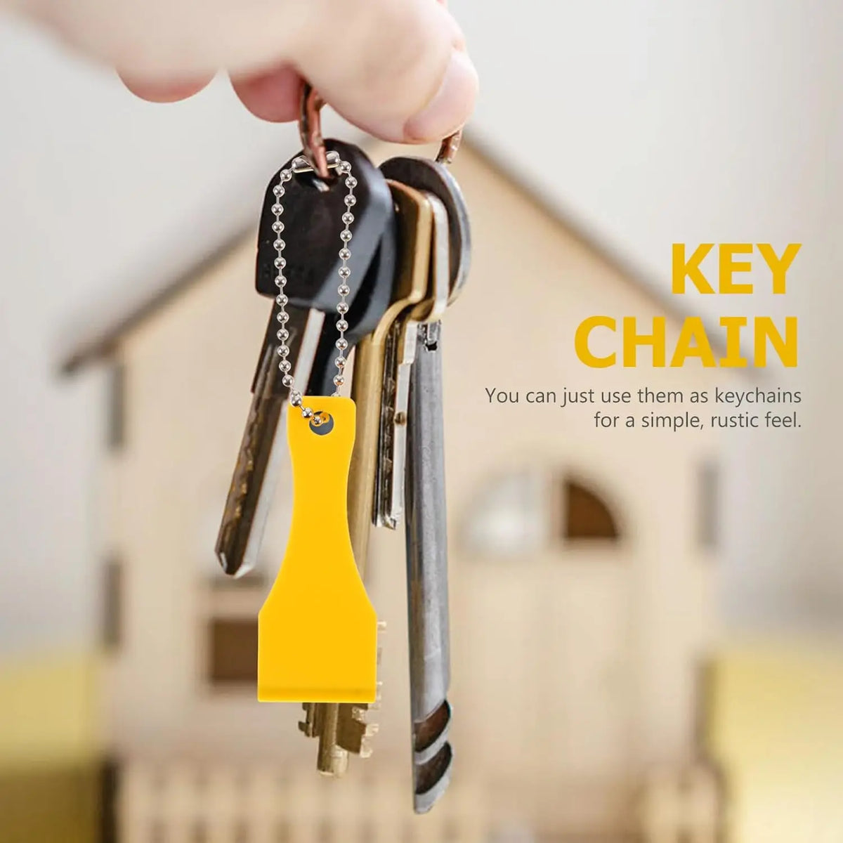 A hand holds a yellow plastic lottery scratcher tool keychain attached to a key chain.