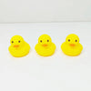 Three bright yellow rubber duck toys are displayed on a white surface.