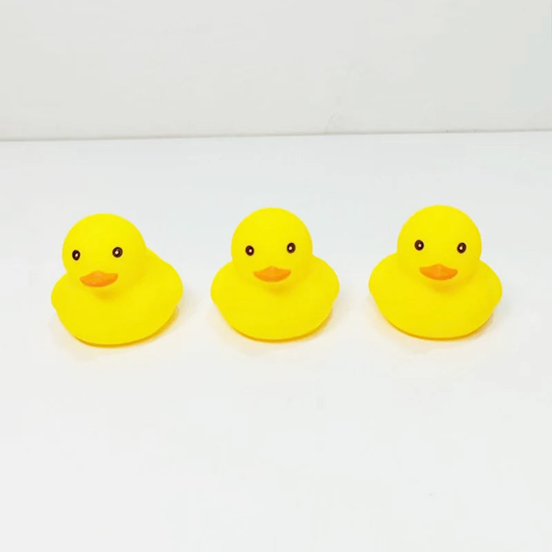 Three bright yellow rubber duck toys are displayed on a white surface.