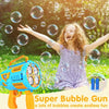 A young girl is joyfully blowing bubbles with a blue bubble gun outdoors.