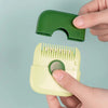 A hand holds a green plastic hair cutting comb and a yellow plastic comb with dual-edge blades.