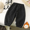 Black fleece-lined polka dot pants with white spots laid out on a white surface.
