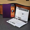 A box of Acoustic Guitar Strings with a purple label and several white string packages is displayed on a dark surface.