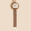 A tan elephant pacifier holder featuring a fluffy gold-brown elephant head and a brown strap with a white cord.