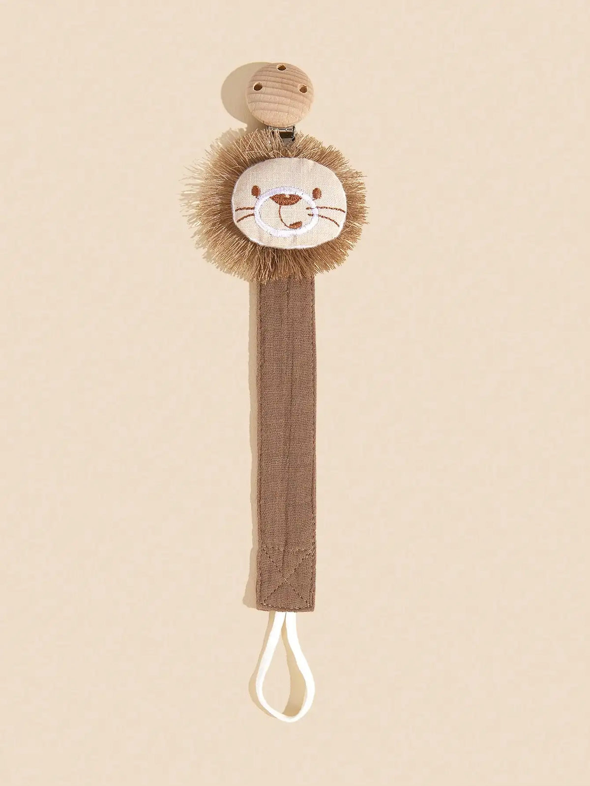 A tan elephant pacifier holder featuring a fluffy gold-brown elephant head and a brown strap with a white cord.
