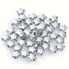 A pile of silver-colored acrylic star and heart spacer beads for jewelry making.