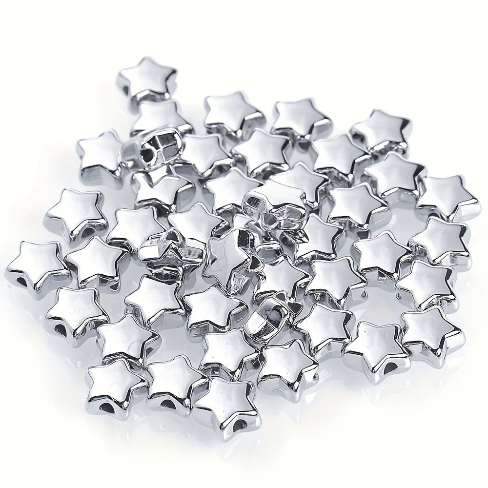 A pile of silver-colored acrylic star and heart spacer beads for jewelry making.