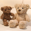 Two fluffy teddy bears, one brown and one beige, sitting side by side on a white surface.