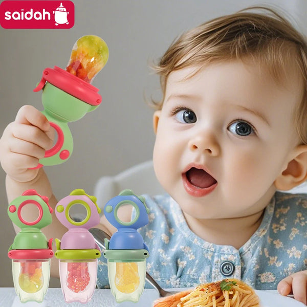 A baby is holding a green dinosaur-shaped silicone feeder filled with fruit or vegetables.