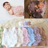 A collection of lace baby rompers and matching headbands in various pastel shades displayed on a wooden board.