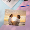 A jigsaw puzzle featuring a photo of two people looking at each other, set on a pink surface.