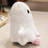 A white ghost plush toy with black eyes and pink accents resting on a light-colored surface.