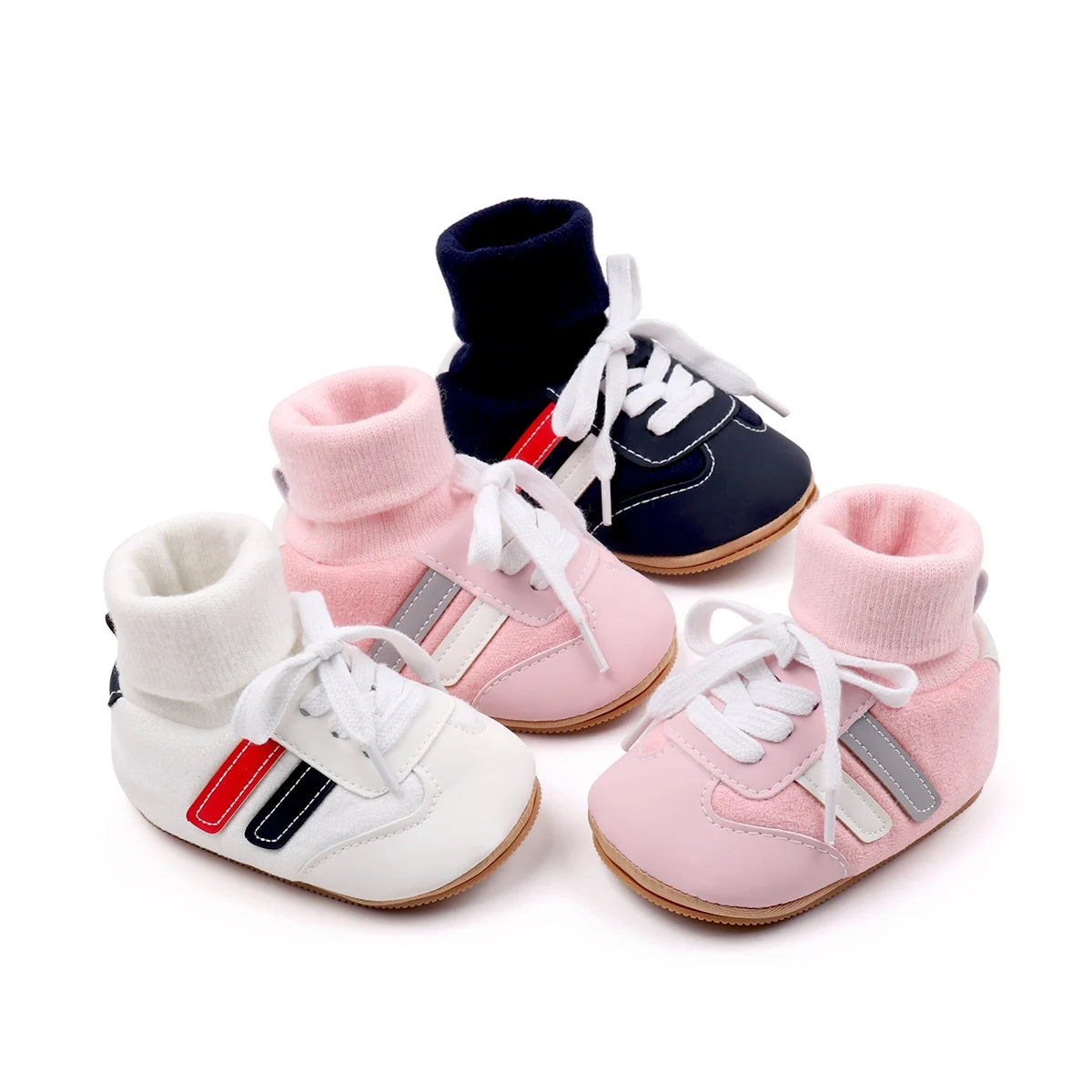 A set of pink and navy ankle-hugging baby booties with white laces and anti-slip soles.