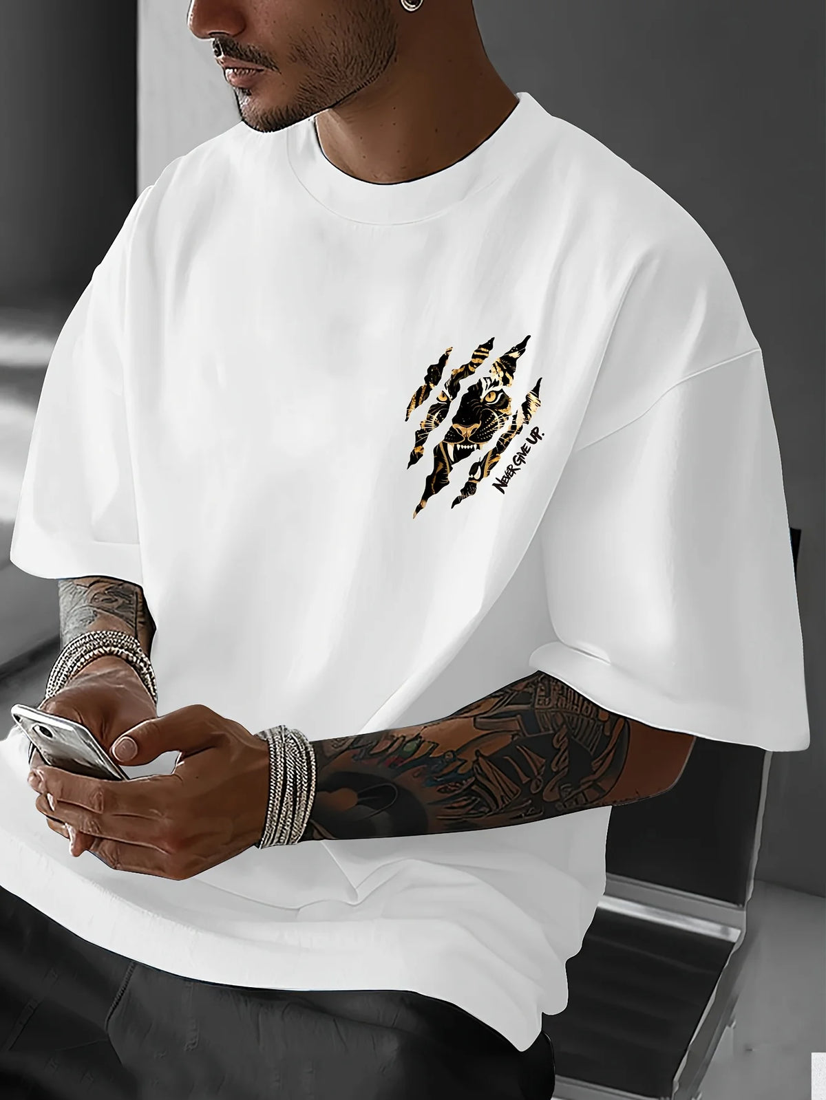 A man wearing a white Tiger Claw Never Give Up graphic cotton t-shirt, showing his arm tattoos.