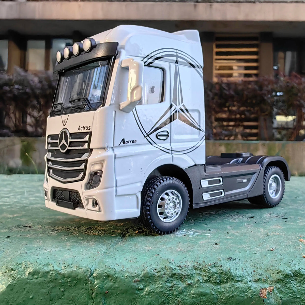 A white 1:50 scale diecast model of a Mercedes-Benz Actros container truck with lights and sounds.