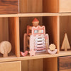 A wooden rocket stacking toy with shape sorter pieces in pink and natural wood colors displayed on a shelf.