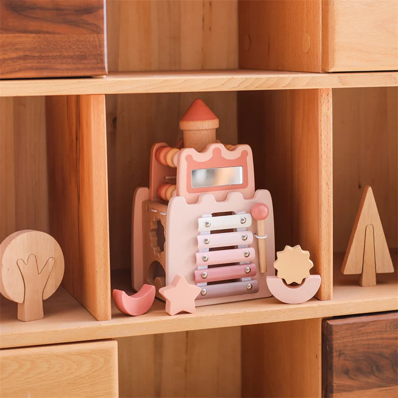 A wooden rocket stacking toy with shape sorter pieces in pink and natural wood colors displayed on a shelf.