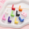 Colorful acrylic letter beads in various colors and shapes arranged on a white tray.