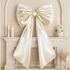 Oversized creamy white satin bow decoration displayed on a white mantelpiece