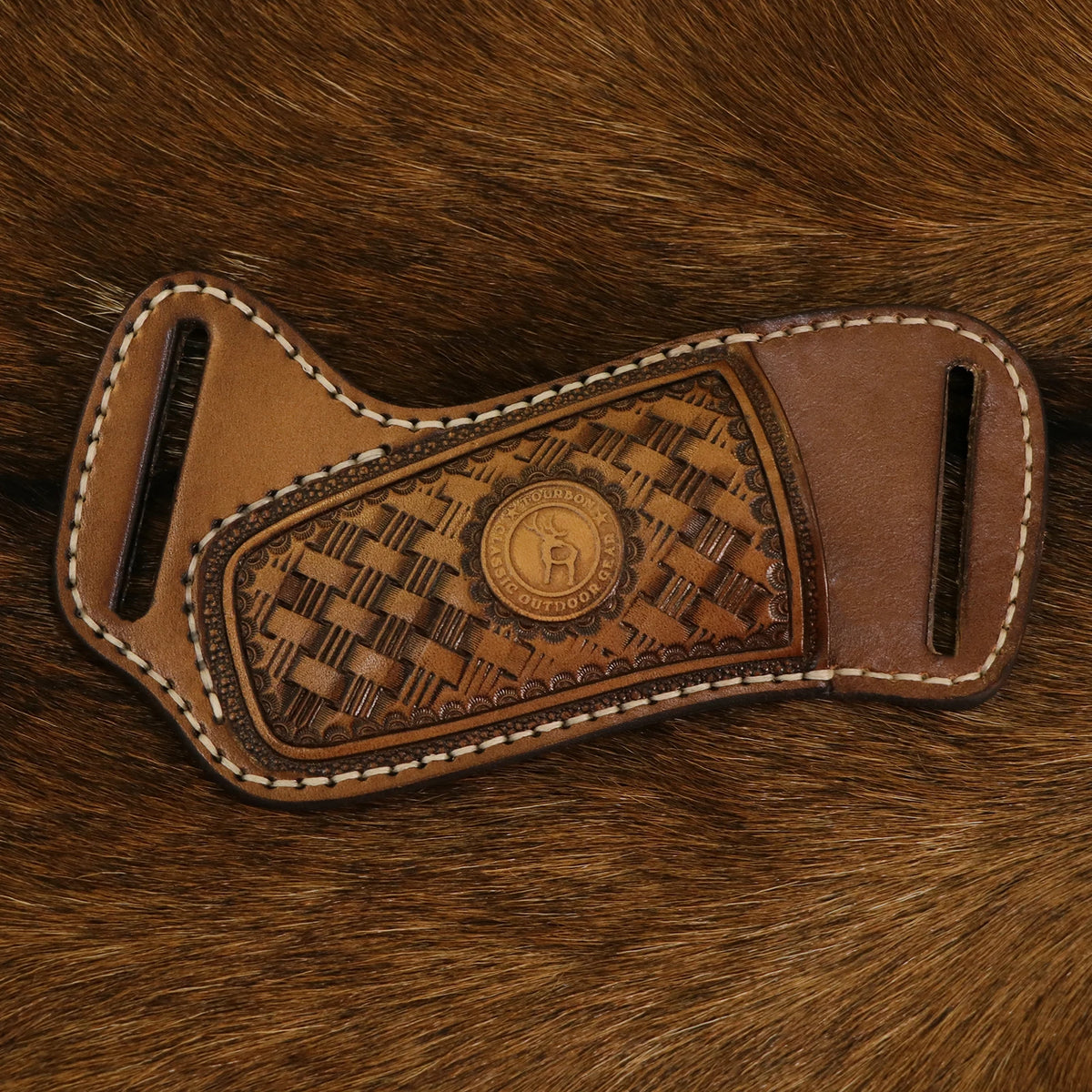 A handcrafted brown leather knife sheath with a belt loop featuring an embossed pattern rests on a brown fur background.