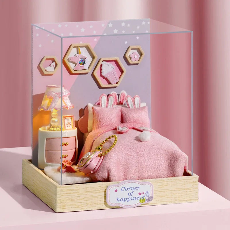 A clear acrylic display box featuring a miniature pink dollhouse with hexagonal window cutouts and soft pink bedding.