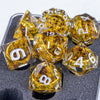 A set of golden resin dice shaped like pyramids with elven numbers, resting on a dark surface.