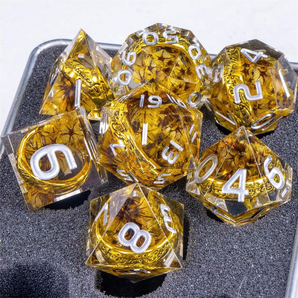 A set of golden resin dice shaped like pyramids with elven numbers, resting on a dark surface.