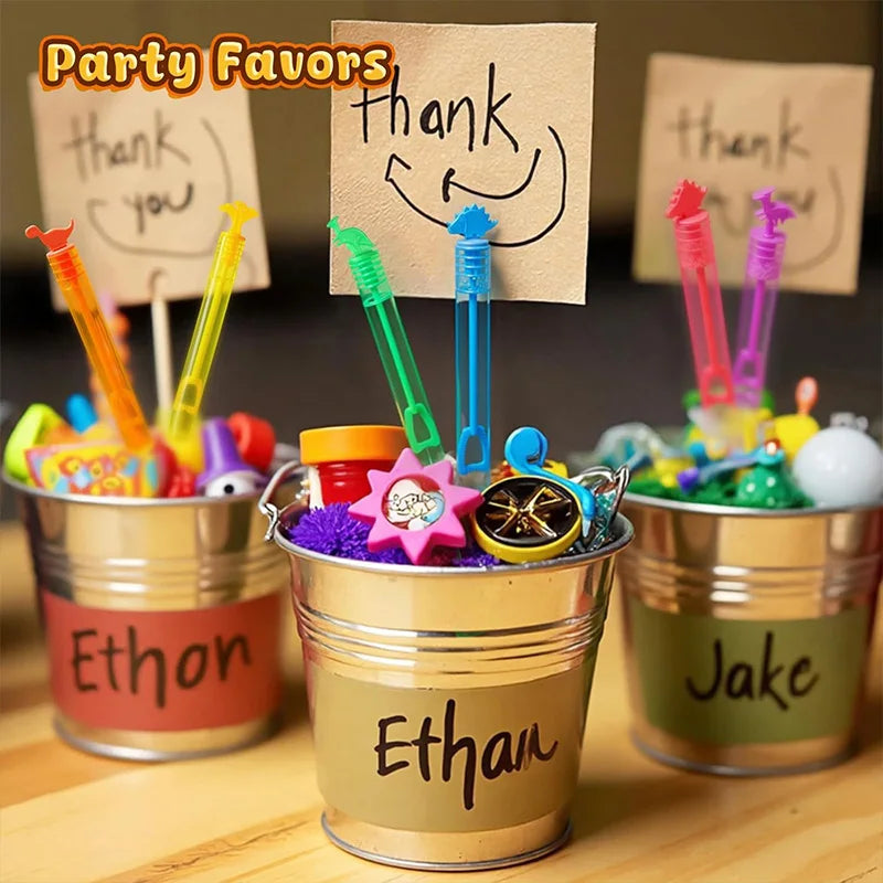 Party favors featuring colorful dinosaur bubble bottles and thank you notes in gold and green tones.