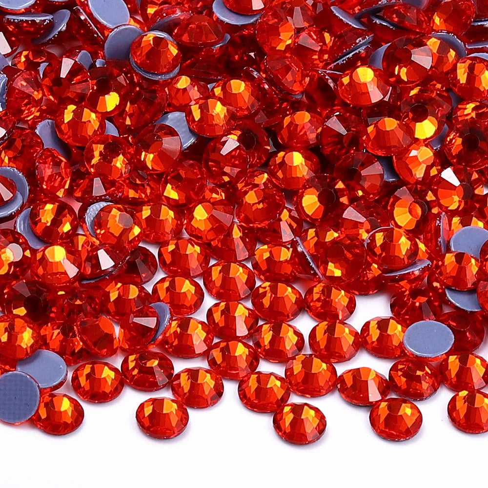 A close-up view of small, faceted glass crystal hot fix rhinestones in various shades of bright orange and red.